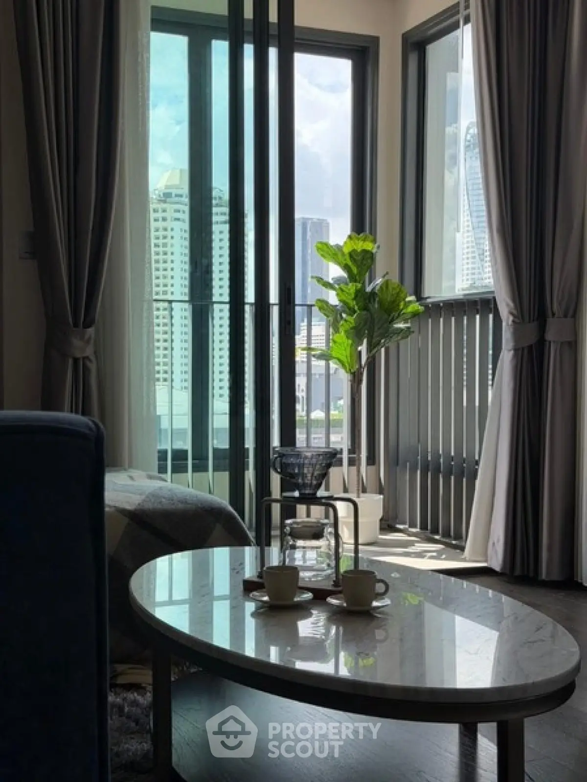 Modern living room with large windows and city view, featuring elegant decor and natural light.