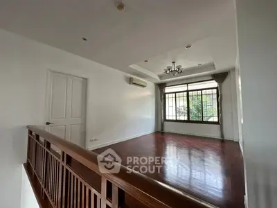 Spacious empty room with wooden flooring and large window, ideal for customization.