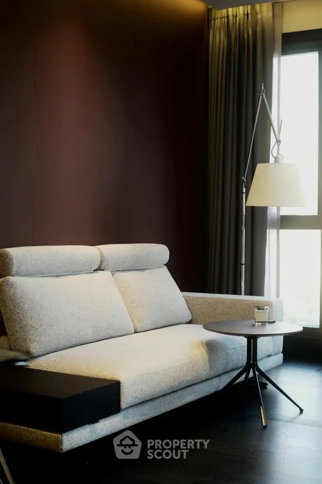 Modern living room with stylish sofa and floor lamp by large window.