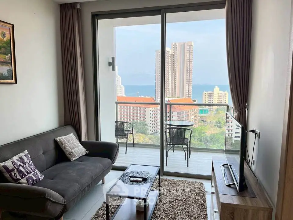 Modern living room with stunning balcony view of cityscape and ocean.