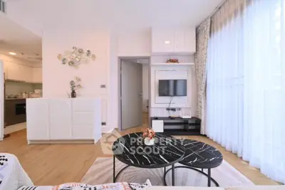 Modern living room with stylish decor and natural light, featuring a sleek TV setup and elegant furniture.