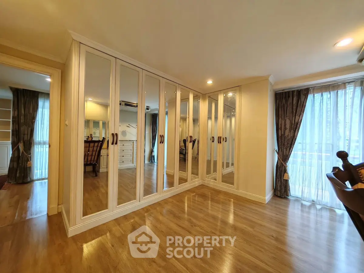 Spacious bedroom with mirrored wardrobes and elegant wooden flooring