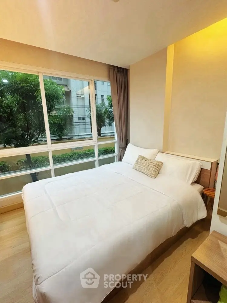 Cozy bedroom with large window and garden view in modern apartment