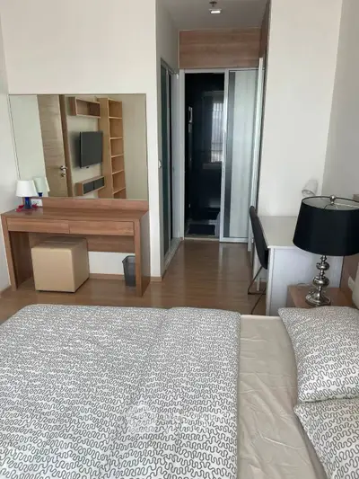 Modern bedroom with stylish decor and workspace, featuring a cozy bed and sleek furniture.