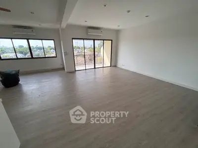 Spacious empty living room with large windows and balcony access