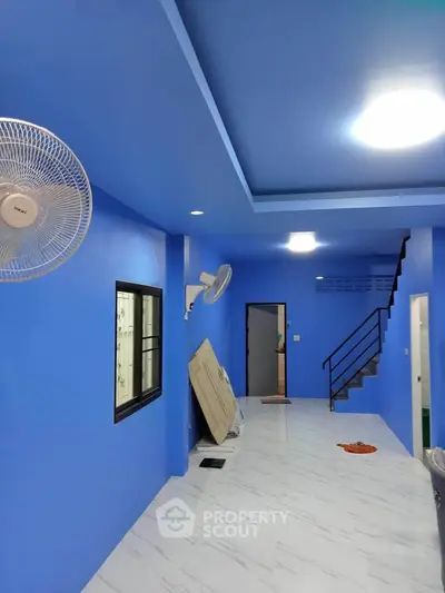 Spacious blue interior with modern staircase and ceiling fans, ideal for contemporary living.