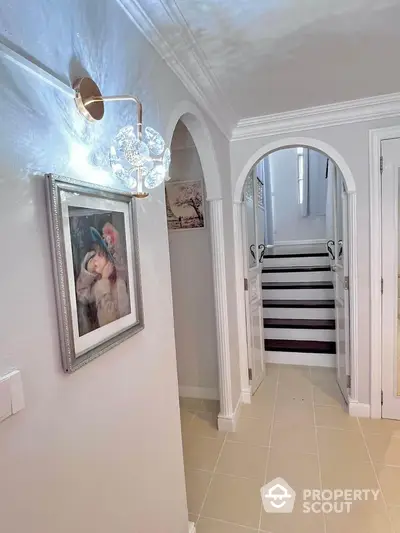 Elegant hallway with archways and modern lighting leading to staircase