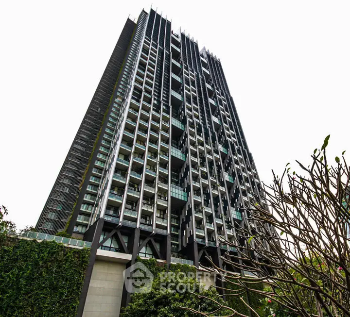 Stunning modern high-rise building with lush greenery at the base, showcasing architectural elegance.