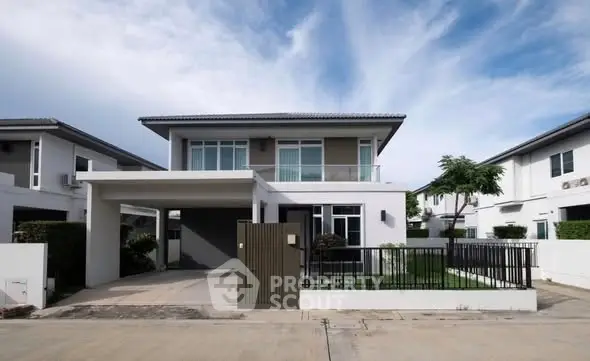 Modern two-story house with sleek design and spacious driveway in a suburban neighborhood.