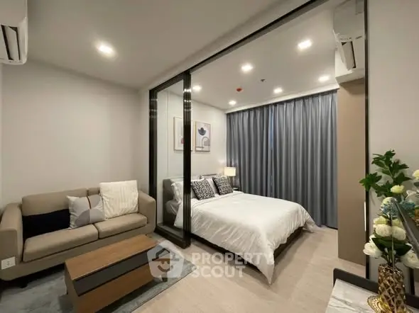 Modern bedroom with glass partition and cozy living area, featuring elegant decor and ambient lighting.
