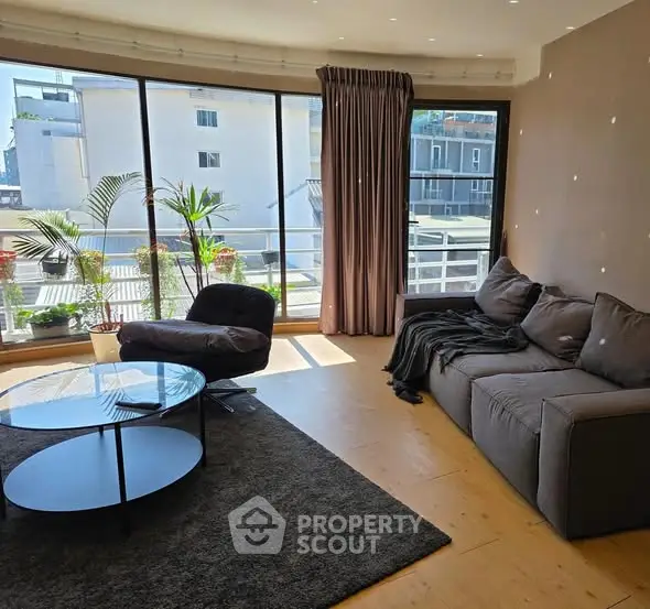 Spacious living room with large windows and modern furniture, offering a bright and inviting atmosphere.