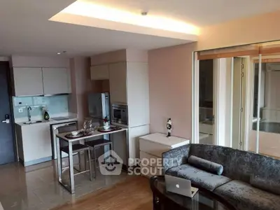 Modern open-layout living room and kitchen with sleek furniture and natural light.