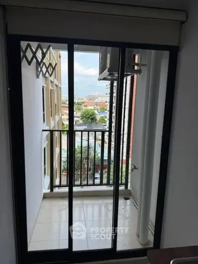 Modern apartment balcony with city view and sliding glass doors.