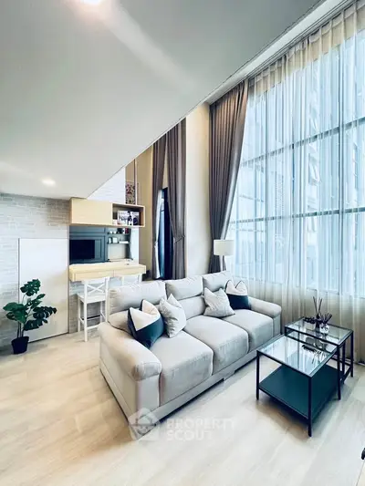 Spacious modern living room with high ceilings and large windows, featuring elegant decor and natural light.