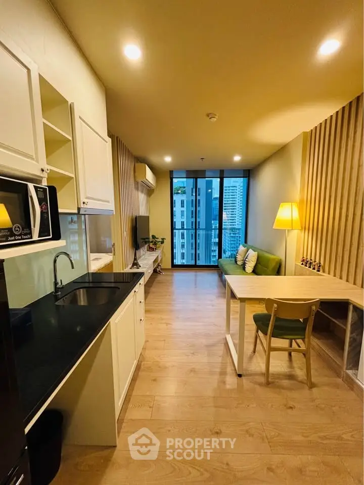 Modern open-plan living room with kitchen and city view, featuring stylish decor and ample natural light.