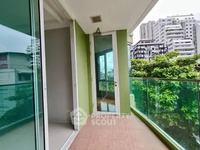 Spacious balcony with glass railing and city view in modern apartment