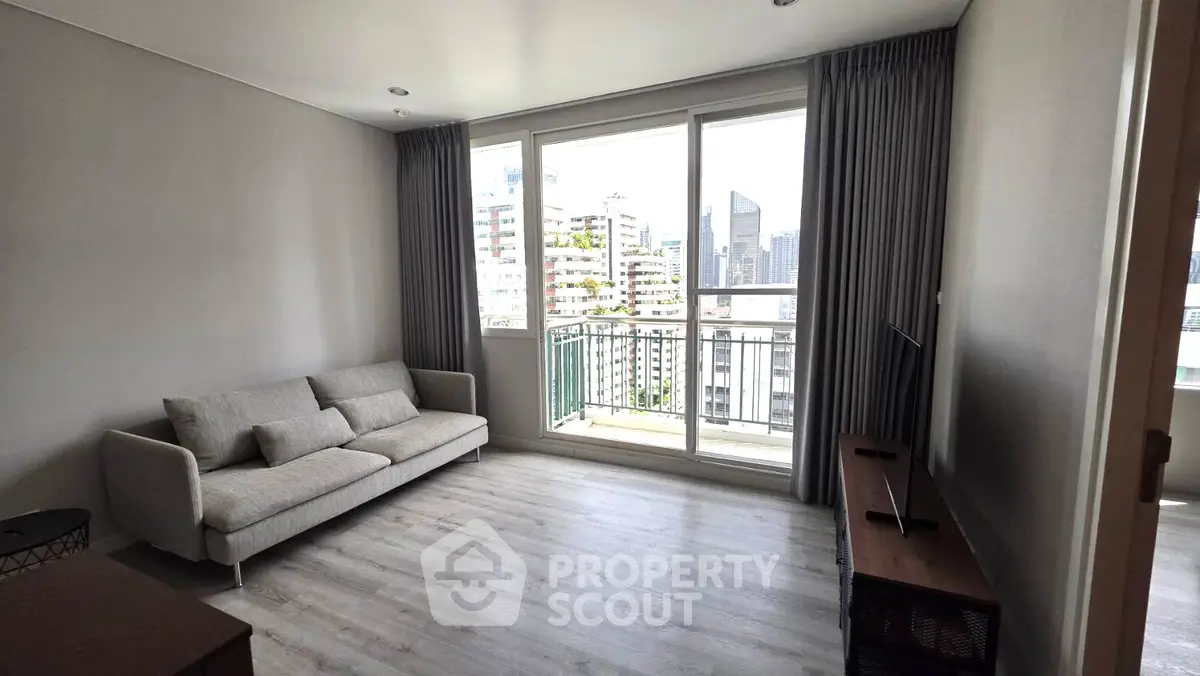 Modern living room with large windows and city view, featuring a cozy sofa and sleek TV stand.