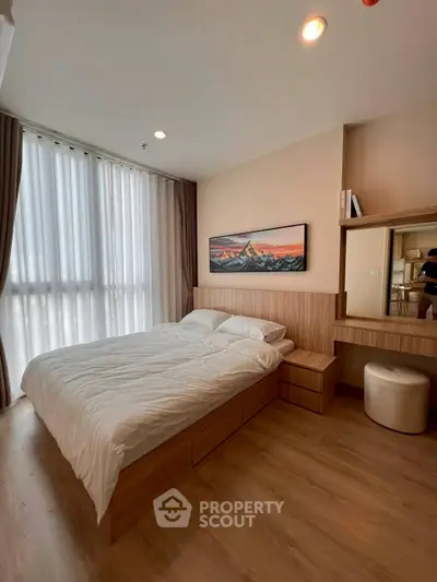 Modern bedroom with large window and stylish decor in a cozy apartment.