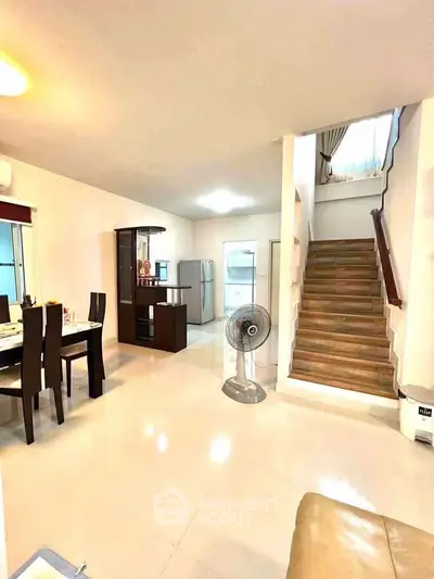 Spacious open-plan living area with dining set and modern kitchen appliances.