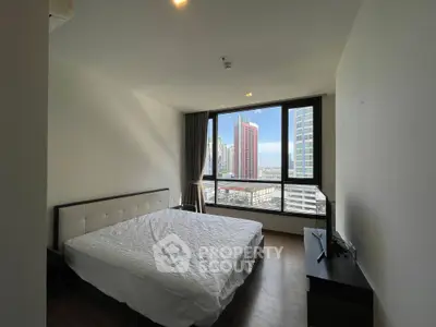 Spacious bedroom with large window offering stunning city view in modern apartment.