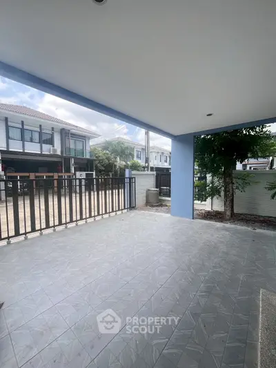 Spacious covered patio with tiled flooring and view of modern residential neighborhood.
