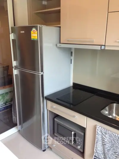 Modern kitchen with stainless steel fridge, microwave, and sleek cabinetry
