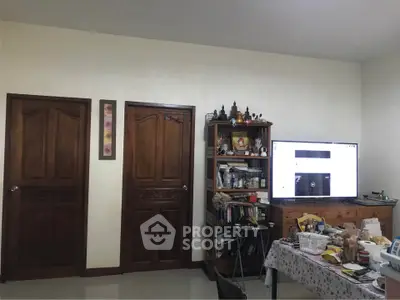 Cozy living room with wooden doors and large TV, ideal for relaxation.