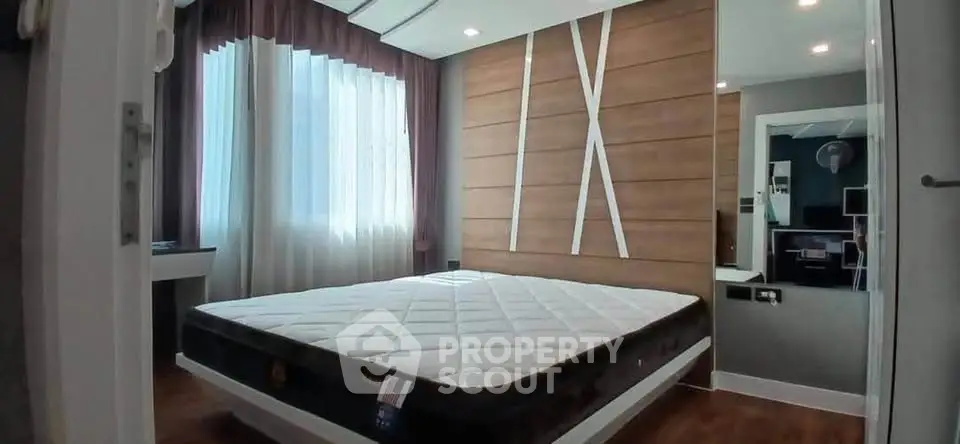 Modern bedroom with stylish wooden accent wall and large window for natural light.