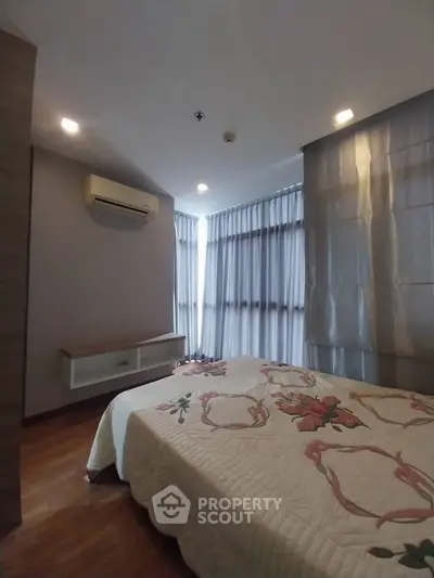 Cozy bedroom with modern decor and large windows for natural light.
