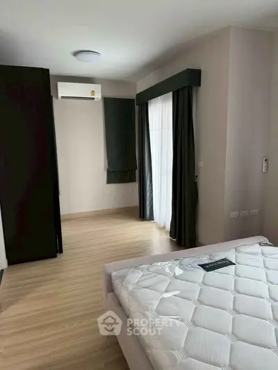 Spacious bedroom with modern design and natural light, featuring a comfortable bed and sleek flooring.