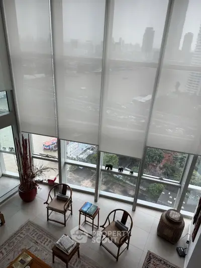 Luxurious high-rise living room with panoramic city and river views, featuring elegant seating and floor-to-ceiling windows.