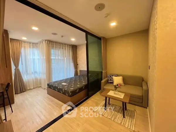 Modern studio apartment with cozy living area and bedroom separated by glass partition.