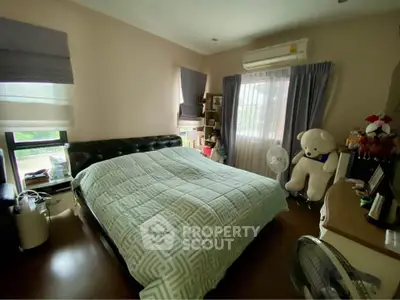 Cozy bedroom with large bed, air conditioning, and natural light from windows.