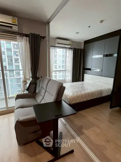 Modern studio apartment with large windows and sleek furniture in urban setting.