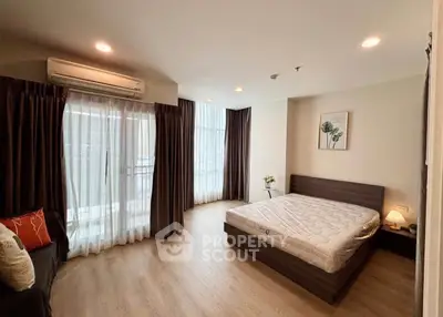Spacious bedroom with large windows and modern decor in a stylish apartment.