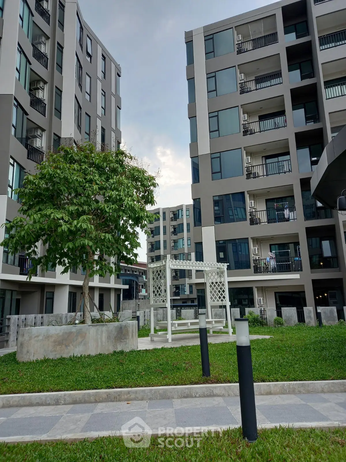 Modern apartment complex with lush green courtyard and contemporary architecture.