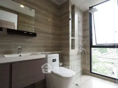 Modern bathroom with sleek fixtures and large window offering natural light and outdoor view.