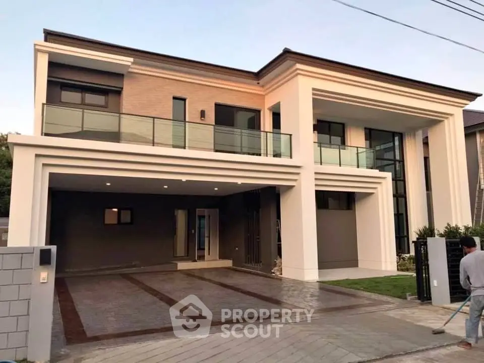 Modern two-story house with spacious driveway and elegant balcony.