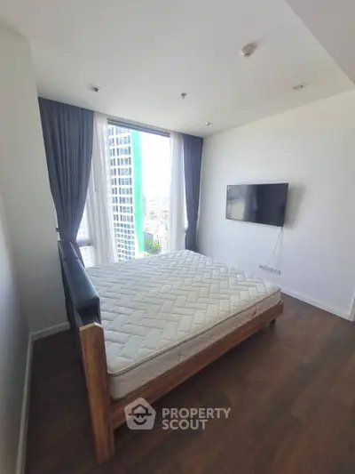 Modern bedroom with large window and city view, featuring a wall-mounted TV and stylish wooden bed frame.
