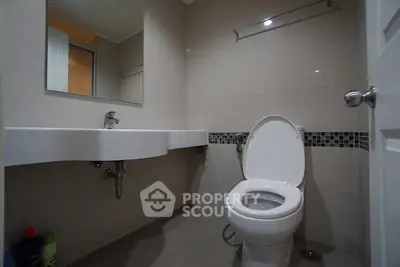 Modern bathroom with sleek fixtures and neutral tiles, featuring a wall-mounted sink and toilet.