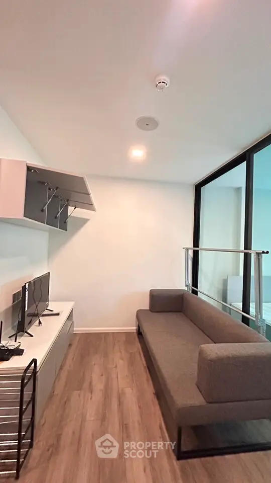 Modern living room with sleek furniture and wooden flooring, featuring a cozy sofa and wall-mounted shelves.