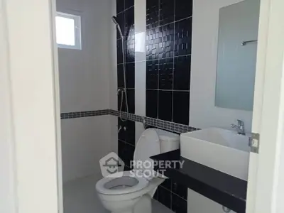 Modern bathroom with sleek black and white tiles and contemporary fixtures.