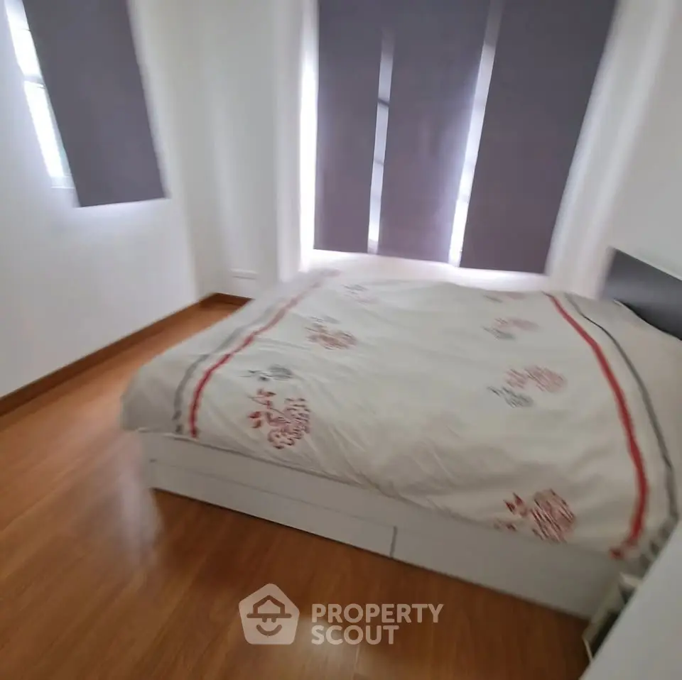 Cozy bedroom with wooden flooring and modern decor, featuring a comfortable bed and ample natural light.