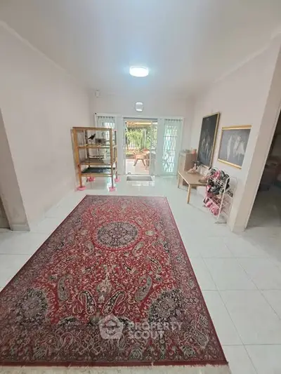 Spacious living room with elegant red carpet and garden view, perfect for family gatherings.