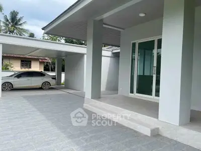 Modern home exterior with spacious carport and sleek sliding glass doors.