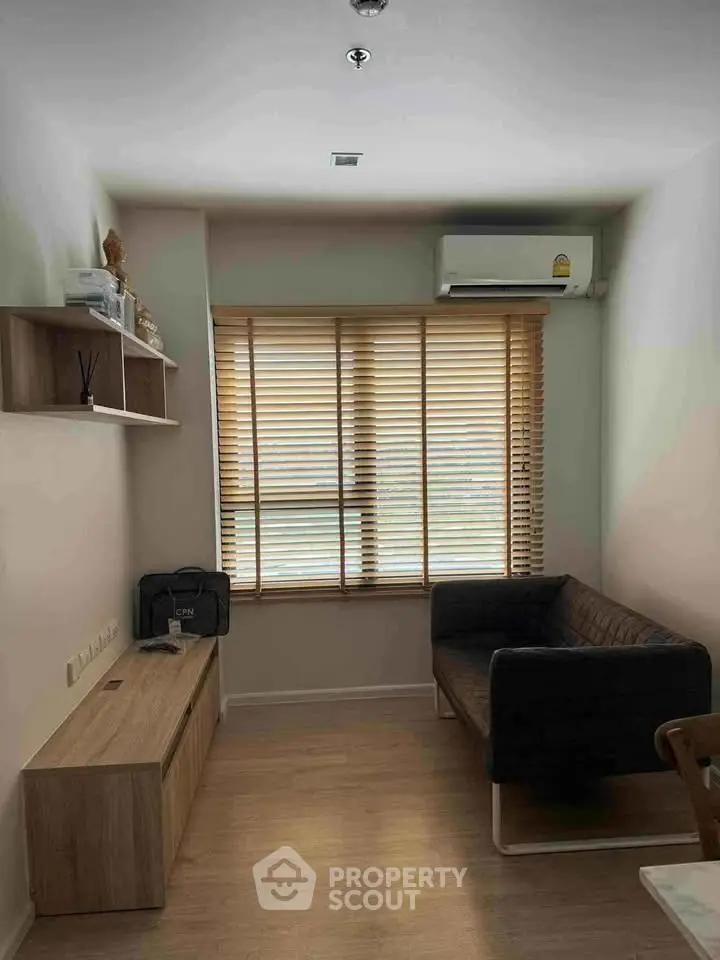 Cozy living room with modern sofa, wooden blinds, and air conditioning unit.