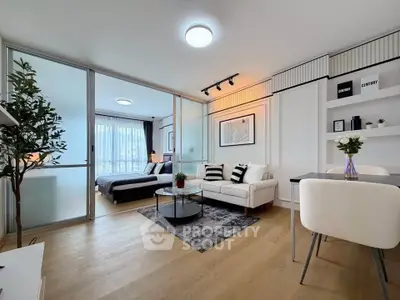 Modern open-plan living room with stylish decor and sliding glass doors leading to a cozy bedroom.