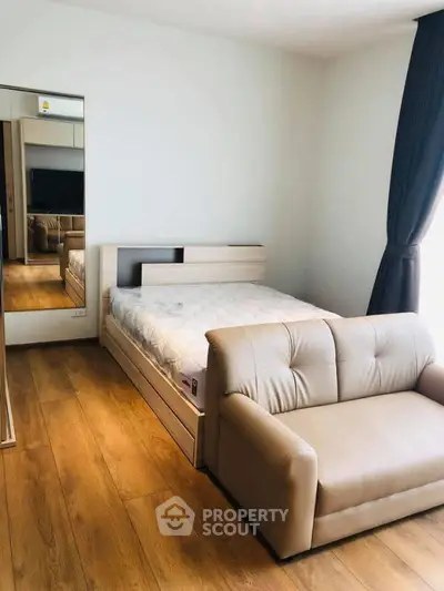 Modern bedroom with wooden flooring and cozy sofa in a bright apartment