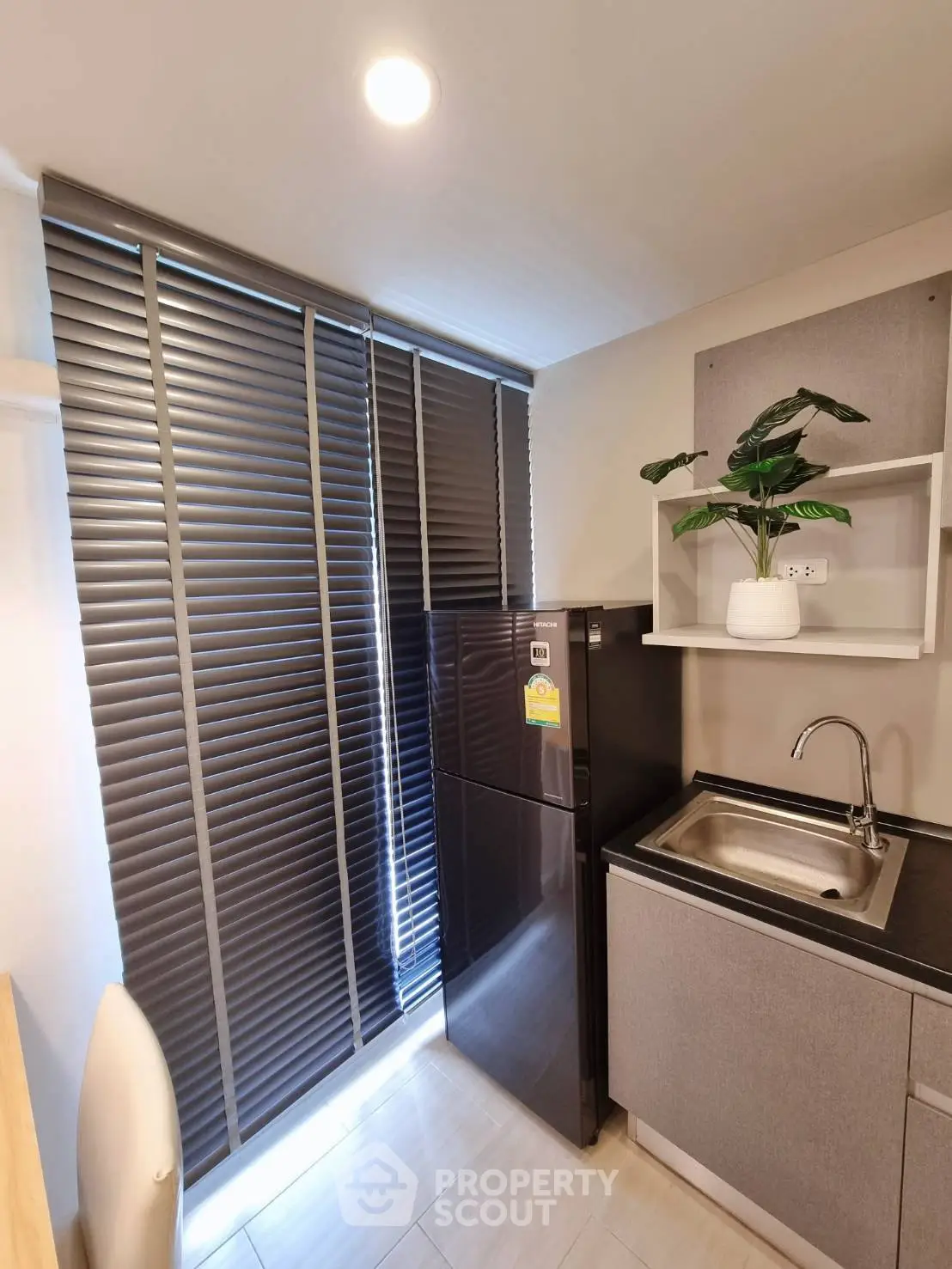 Modern kitchen with sleek fridge and stylish blinds, perfect for urban living.