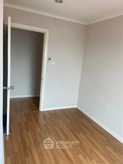 Spacious empty room with wooden flooring and white walls, ideal for customization.